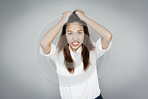 Confuse Asian lady catching her hair wearing white shirt and blu