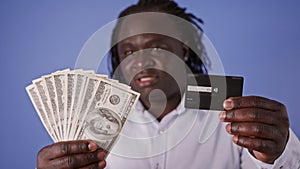 Confused African Man with Credit Card and Money - US Dollars - Cash or Card dillema