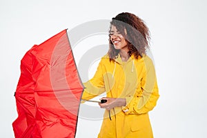 Confused african woman in raincoat close umbrella