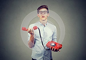 Confused annoyed teenager man with old fashioned telephone