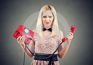Confused annoyed woman with old fashioned telephone