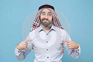 Confused arabian muslim man in keffiyeh kafiya ring igal agal casual clothes isolated on pastel blue background. People