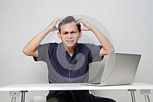 confused asian man in workplace white sitting in front of laptop computer. isolated background