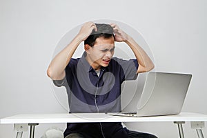 confused asian man in workplace white sitting in front of laptop computer. isolated background