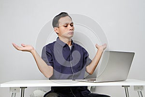 confused asian man in workplace white sitting in front of laptop computer. isolated background