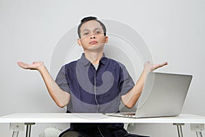 confused asian man in workplace white sitting in front of laptop computer. isolated background