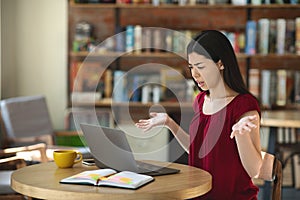 Confused Asian Woman Having Problems With Laptop While Working Remotely In Cafe