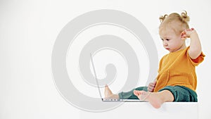 Confused baby girl looks at the laptop screen on white background. User problem related clip