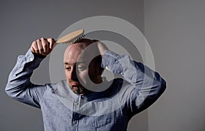 Confused bald man with hair brush