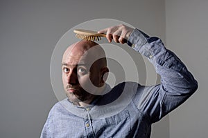 Confused bald man with hair brush