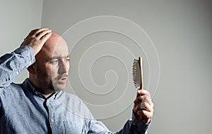 Confused bald man with hair brush