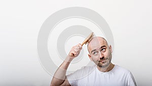 Confused bald man with hair brush