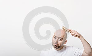 Confused bald man with hair brush