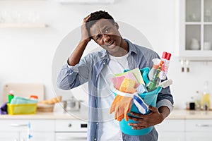 Confused black guy holding busket with cleaning tools