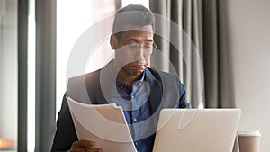 Confused black male employee feel unsure reading paperwork documents photo