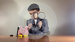 Confused boy in a suit lifting piggy bank after coin did not stay in it. Stagflation, low economic growth or bad