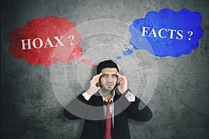 Confused businessman with hoax or fact photo