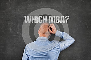 Confused Businessman Scratching Head Under MBA Text On Blackboard photo