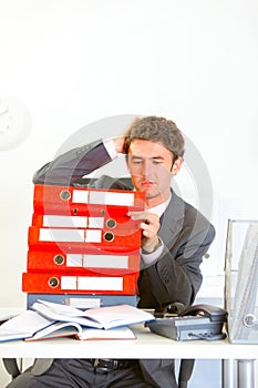 Confused businessman sitting at desk with folders