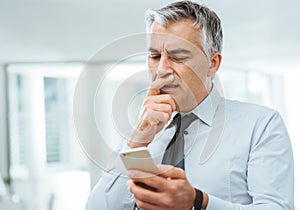 Confused businessman using a smart phone