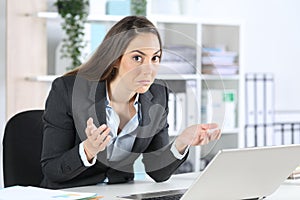 Confused businesswoman looking camera with laptop at office photo