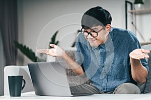 Confused clueless man using laptop computer for Video conference call shrugging shoulders making no idea, whatever gesture I don`