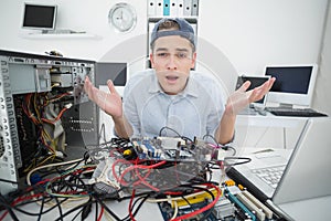 Confused computer engineer working on broken console with laptop