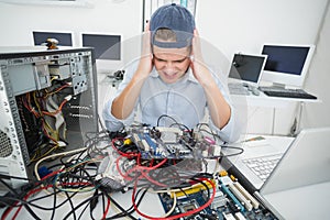 Confused computer engineer working on broken console with laptop