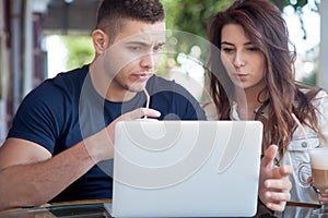 Confused couple looking at laptop at a cafe