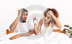 Confused couple missed ringing of alarm clock in bed