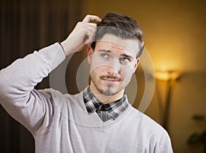 Confused or doubtful young man scratching his head and looking up