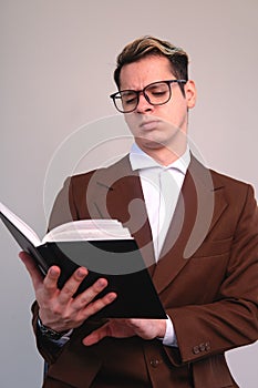 Confused elegant man attentively reading a book. A man in a suit, shirt and glasses studying. Studious man reading the