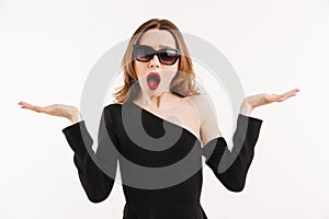 Confused elegant woman in dress and sunglasses shrugs her shoulders