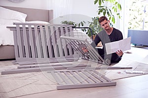 Confused Father To Be Looking At Instructions For Self Assembly Baby Cot