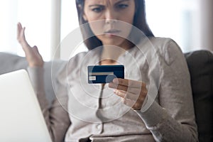 Confused female customer holding credit card angry with online payment photo