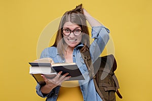 Confused female student with a pile of books rubbing her head troubled with exam