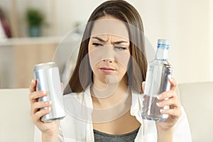 Confused girl deciding between soda refreshment and water photo