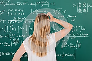 Confused Girl Looking At Blackboard In Classroom