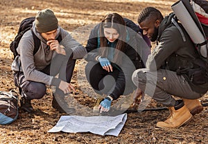 Confused hikers looking at map, lost in forest