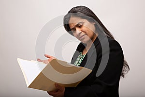 Confused Hispanic Businesswoman Looks Through Folder