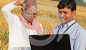 Confused Indian farmer Scratching his head while banker or corporate government officer discussing on laptop about crop yield,