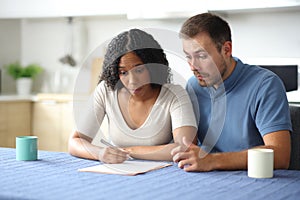 Confused interracial couple reading contract in a kitchen