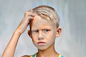 Confused junior schooler puts hand on head looking in camera