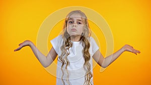 Confused kid shrugging on yellow background, lack of ideas, feeling uncertain