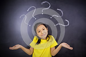 Confused little girl standing with question marks