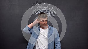 Confused male scratching head against blackboard, lack of experience, solution