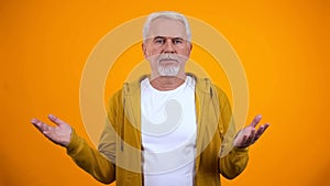 Confused man feeling injustice and helpless, no idea gesture, yellow background