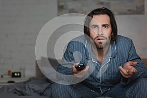 Confused man with insomnia holding remote