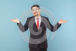 Confused man with mustache standing with spread hands, looking at camera, shrugging shoulders.