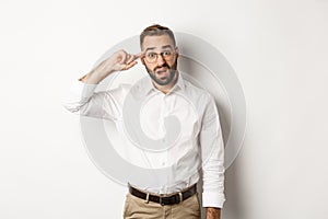 Confused man pointing at head, scolding employee, reaction on something strange, standing over white background